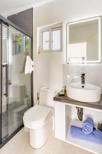 een witte badkamer met een toilet en een wastafel bij Arubini - aruba in Palm-Eagle Beach +66 foto's