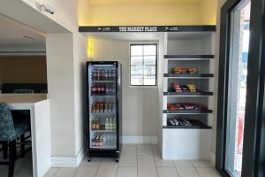 a refrigerator in a room with a shelf of drinks at Super 8 by Wyndham Nacogdoches Near University in Nacogdoches