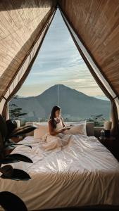 a woman sitting on a bed in a tent at Batur Cabins in Kintamani