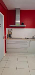 a kitchen with red walls and a white tile floor at Bambou971 in Le Gosier