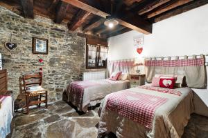 a bedroom with two beds and a stone wall at Regalate Paz 2 in Arguis