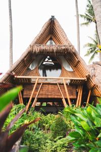 a building with a straw roof with a window at Batu Kayu Medewi in Medewi