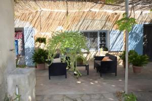 Un patio con sillas y plantas en macetas debajo de una carpa. en Le Mas Des Glycines, en Les Vignères