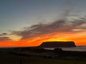 a sunset over the ocean with a mountain in the background at Beachscape in Stanley