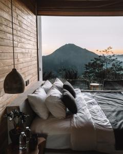 a bed in a room with a large window at Batur Cabins in Kintamani