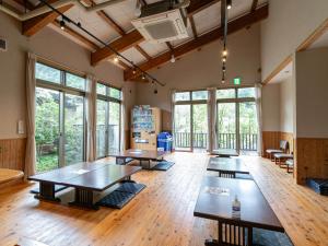 een grote kamer met tafels, stoelen en ramen bij Fontana no Oka Kamou in Aira