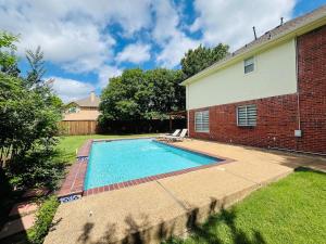 a swimming pool in a yard next to a brick building at Pickleball , Pool , Bkyd Oasis , Centrally Located in Frisco