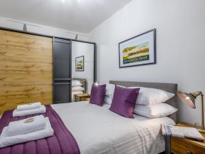 a bedroom with a large bed with purple pillows at 4 Bed in Holt 79034 in Holt