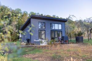 a small gray house with windows and a table at Lodge para parejas con jacuzzi hidromasaje in Panguipulli