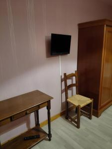 a room with a table and a chair and a tv at Chambre Château in Augnat