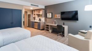 une chambre d'hôtel avec deux lits, un bureau et une télévision dans l'établissement Candlewood Suites - Guadalajara Galerias by IHG, à Guadalajara