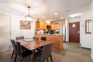 Una cocina y un comedor con mesa y sillas de madera. en Glacier Lodge 216 by Outpost Whistler, en Whistler