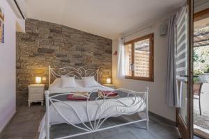 a bedroom with a white bed and a brick wall at La Peireta- maison éco responsable in Saint Alban Auriolles +32 photos