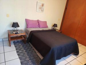 - une chambre avec un lit doté d'oreillers roses et d'une table dans l'établissement Casa Luna, à Morelia