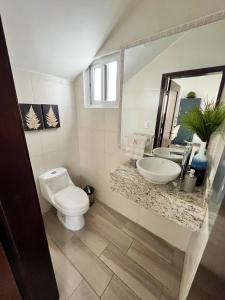 a bathroom with a toilet and a sink and a mirror at Modern Room-Gated Community in San Pedro Sula +5 photos