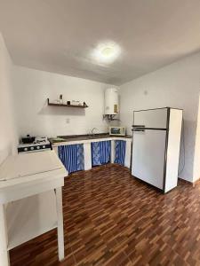a kitchen with a white refrigerator and a wooden floor at Depto Santa Cruz in Villa Santa Cruz del Lago