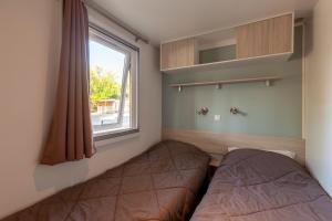 een slaapkamer met twee bedden en een raam bij Lou Soleil 80 in Carry-le-Rouet