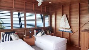 two beds in a room with wooden walls and windows at Northview Villa in Palm Beach