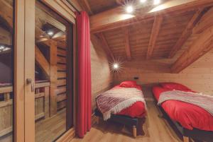 two beds in a log cabin with wooden ceilings at Chalet La Rocca in La Chapelle-dʼAbondance