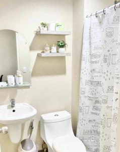 a bathroom with a toilet and a sink and a shower curtain at Urban Oasis in Cagayan de Oro City in Cagayan de Oro
