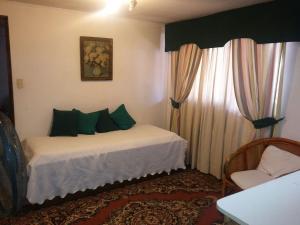 a bedroom with a bed with green pillows and a window at Apart Hotel Punto Real in Curicó
