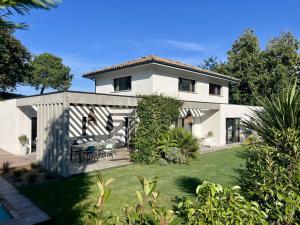 a white house with a table and chairs in a yard at Villa 8 pers à Seignosse avec piscine chauffée et clim - FR-1-791-44 in Seignosse