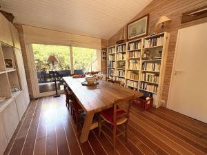 a dining room with a wooden table and book shelves at Charmante villa familiale au Cap Ferret, proche plages, 9 pers - FR-1-736-68 in Cap-Ferret