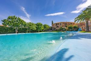 a large pool of blue water with trees and buildings at Calú in L'Alfas del Pi