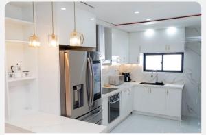 Una cocina con gabinetes blancos y un refrigerador de acero inoxidable. en New family villa with a private pool, en Punta Cana