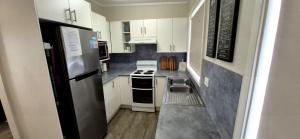 サンクチュアリ・ポイントにあるGreville Getaway - Absolute Waterfrontの小さなキッチン(白いキャビネット、ステンレス製の冷蔵庫付)