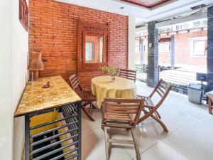 d'une salle à manger avec une table, des chaises et un mur en briques. dans l'établissement Huiz de Rico Guesthouse Syariah near Ambarrukmo Area, à Demangan 18 autres photos