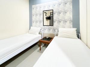 deux lits dans une chambre avec un miroir et une table dans l'établissement Huiz de Rico Guesthouse Syariah near Ambarrukmo Area, à Demangan