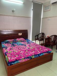 胡志明市Khách Sạn GIANG PHƯỚC HÙNG的卧室里有一张铺着花卉床罩的床