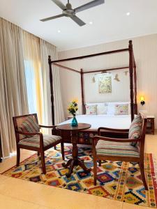 a bedroom with a bed and a table and two chairs at Madhukar Vilas in Vrindāvan