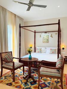 a bedroom with a canopy bed with a table and two chairs at Madhukar Vilas in Vrindāvan +48 photos