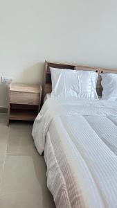 a bedroom with a white bed and a night stand at مسقط العامرات in ‘Udhaybah +7 photos