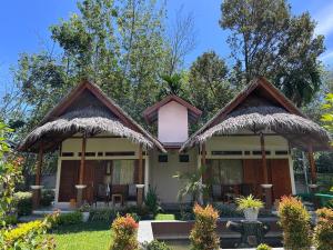 a house with two thatched gazebos at Leuser Inn & Jungle Trekking in Bukit Lawang