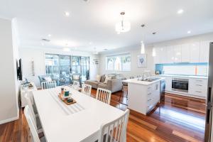 a kitchen and living room with white cabinets and a table at The Lake House - Spacious Group Haven by the Bay in Victor Harbor
