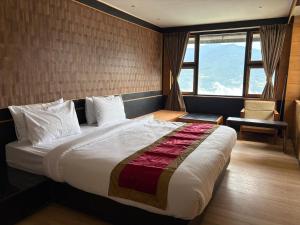 Un dormitorio con una cama grande y una ventana. en Hotel Mist Tree Mountain, en Gangtok