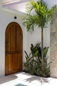 a palm tree next to a wooden door at Villa Nida Premium by Tofino Villas in Uluwatu