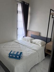 un lit avec une couverture bleue et blanche et une fenêtre dans l'établissement Inapstay - Villa Aura Puncak Landungsari, à Dau