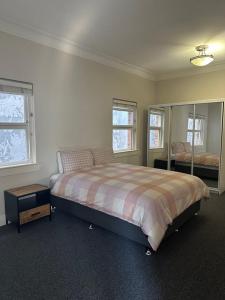 Un dormitorio con una cama grande y dos ventanas. en Riverstone Loft, en Rockhampton