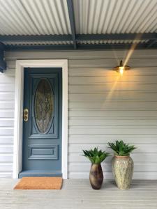 ウェントワース・フォールズにあるWhispering Pines Cottagesのポーチにある青いドアと2つの花瓶