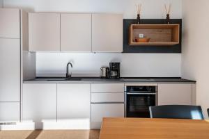 a kitchen with white cabinets and a wooden table at Ferienwohnungen Karin - Gala in Termeno