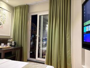 a bedroom with green curtains and a window at SandDune Luxury Suites in Cochin