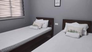 two twin beds in a bedroom with white pillows at Angel's Bed and Breakfast Sipalay in Sipalay +8 photos