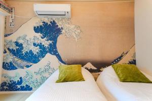 two beds in a room with a painting of a wave at 池袋駅徒歩5分 Mejiro Yasu Hotel in Tokyo