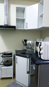 a kitchen with white cabinets and a sink at Cozy Modern Studio Overlooking the Skyline in Molo +2 photos