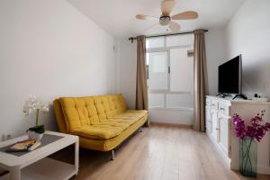 a living room with a yellow couch and a tv at Apartamento Playa Morro Jable 2c in Morro del Jable