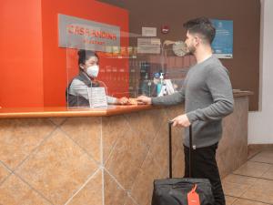 Ein Mann steht an einem Tresen mit einer maskierten Frau in der Unterkunft Casa Andina Standard Puno in Puno